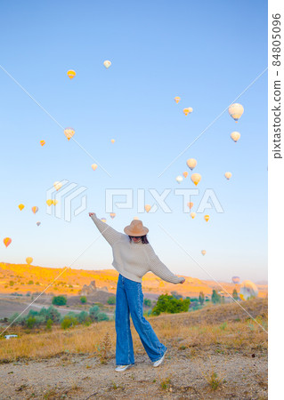 Happy woman during sunrise watching hot air balloons in Cappadocia, Turkey 84805096