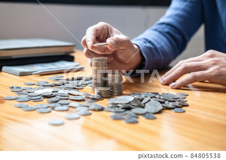 Young man and pile coins to planning growing saving strategy with pile coins for future plan fund of travel, education, home and retirement 84805538