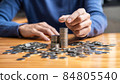 Young man and pile coins to planning growing saving strategy with pile coins for future plan fund of travel, education, home and retirement 84805540