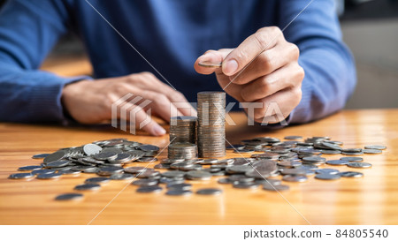 Young man and pile coins to planning growing saving strategy with pile coins for future plan fund of travel, education, home and retirement 84805540
