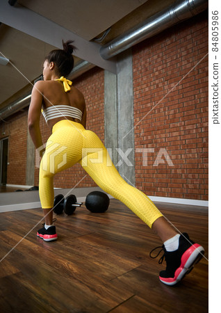 Rear view of an African American beautiful athlete woman with perfect healthy slim body working out, stretching legs and performing lunges in gym club. Active lifestyle concept. 84805986