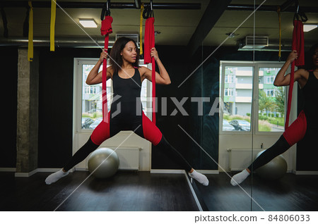 Fit pretty young woman doing fly yoga stretching exercises in a studio. Sport and healthy lifestyle concept 84806033