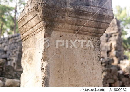 half-erased antique inscription on a stone among the ruins of the ancient city of Phaselis, Turkey 84806082