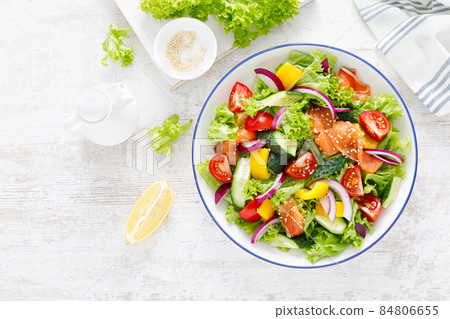Salted salmon salad with fresh green lettuce, cucumbers, tomato, bell pepper and red onion. Ketogenic, keto or paleo diet lunch bowl. Top view 84806655