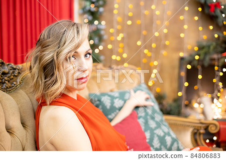 beautiful blonde young woman sitting in a room decorated for the new year celebration beautiful blonde young woman sitting in a room decorated for the new year celebration 84806883