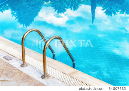 Green palm trees reflexion on a modern outdoor luxurious pool with azure water 84807583