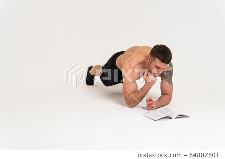 Bodybuilder reads the book on a white background isolated at the bottom of his head on his hands bodybuilder young muscle reader healthy, standing. manager biceps, posing tan Bodybuilder reads the book on a white background isolated at the bottom of his head on his hands bodybuilder young muscle reader healthy, standing. manager biceps, posing tan 84807801