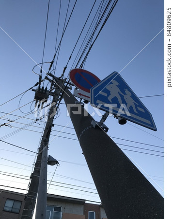 Utility poles and road signs that support the blue sky diagonally 84809625