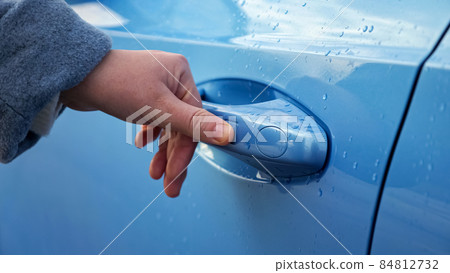 Woman closes automobile driver door covered with rain drops Woman closes automobile driver door covered with rain drops 84812732
