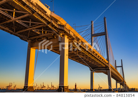 Yokohama Bay Bridge illuminated by the setting sun, Yokohama Port at sunset, waterfront Yokohama Bay Bridge illuminated by the setting sun, Yokohama Port at sunset, waterfront 84813854