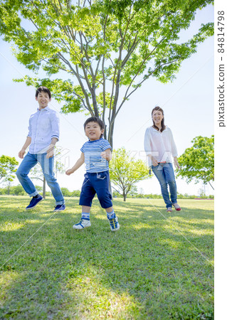 Three-person family playing in a fresh green park 84814798