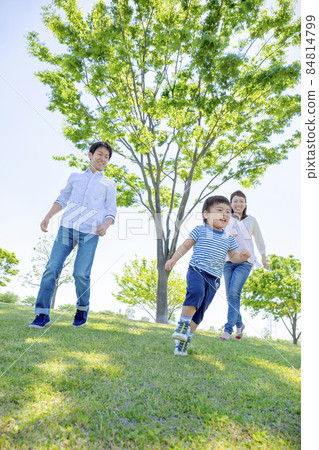 Three-person family playing in a fresh green park Three-person family playing in a fresh green park 84814799