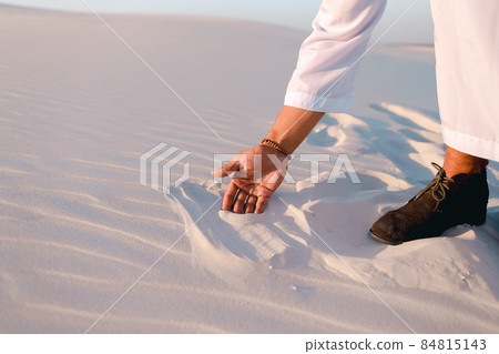 Close-up shot of portrait and hands of young Arab guy in sandy desert on clear summer day in open air. Close-up shot of portrait and hands of young Arab guy in sandy desert on clear summer day in open air. 84815143