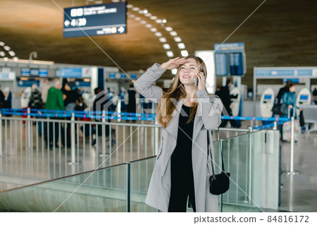 Girl talking by smartphone and looking for friend at aiport. 84816172