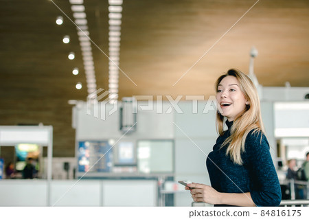 Caucasian girl chatting by smarphone at airport hall. Caucasian girl chatting by smarphone at airport hall. 84816175