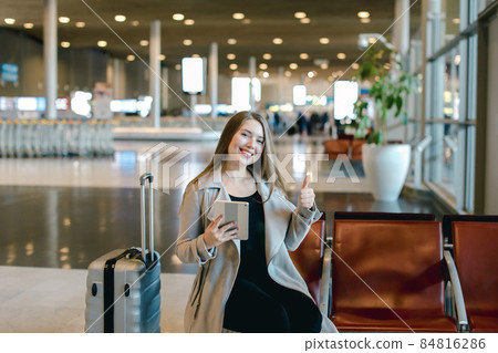Woman using internet by tablet in airport hall near valise and s 84816286