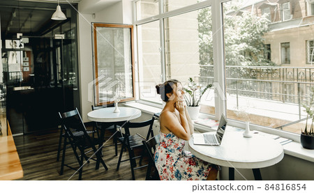 Young caucasian girl sitting with laptop at cafe. 84816854