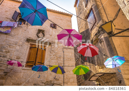 Colorful umbrellas hanging in a stone street in the historic cen 84818361