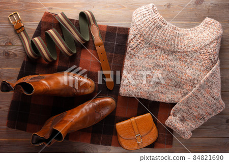 Leather boots with sweater and female clothes at wood table. Travel concept of retro clothing Leather boots with sweater and female clothes at wood table. Travel concept of retro clothing 84821690