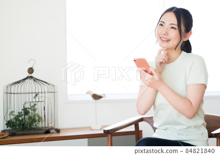 一個女人坐在椅子上操作智能手機 一個女人坐在椅子上操作智能手機 84821840