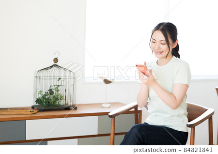 一個女人坐在椅子上操作智能手機 一個女人坐在椅子上操作智能手機 84821841
