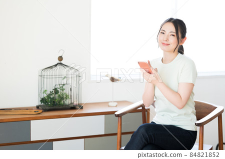 一個女人坐在椅子上操作智能手機 一個女人坐在椅子上操作智能手機 84821852