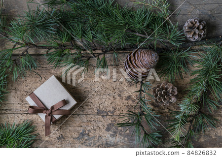 Christmas present box, pine tree branch and cones on wooden table Christmas present box, pine tree branch and cones on wooden table 84826832