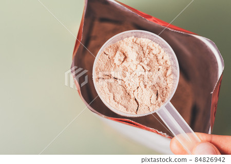 Close-up whey protein measuring spoon over open package bag 84826942