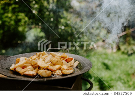 fried potatoes with a crust cooked in a large black pan on the grill 84827509