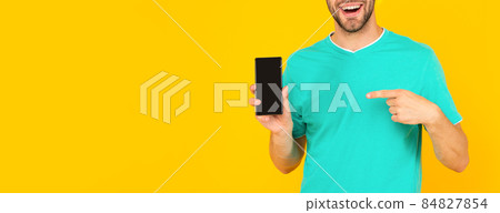 cropped man presenting phone screen. guy point finger on smartphone on yellow background. cropped man presenting phone screen. guy point finger on smartphone on yellow background. 84827854