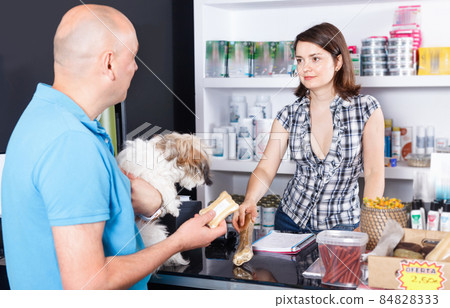 Young woman seller offering goods to man customer in pet store 84828333