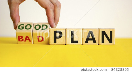 Good a bad plan symbol. Male hand flips wooden cubes and changes words 'bad plan' to 'good plan'. Beautiful yellow table, white background, copy space. Business and good plan concept. 84828895