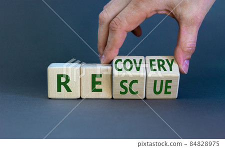 Recovery and rescue symbol. Businessman turns cubes and changes the word 'recovery' to 'rescue'. Beautiful grey background. Business and recovery - rescue concept. Copy space. 84828975