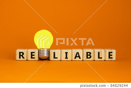 Reliable symbol. Wooden cubes with the word reliable. Yellow light bulb. Beautiful orange background, copy space. Business and reliable concept. Reliable symbol. Wooden cubes with the word reliable. Yellow light bulb. Beautiful orange background, copy space. Business and reliable concept. 84829244