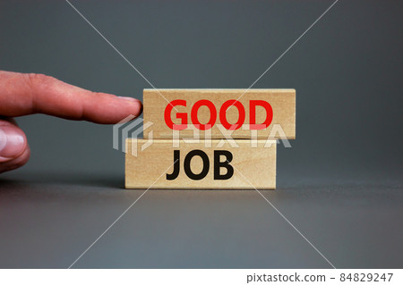 Good job symbol. Concept words 'good job' on wooden blocks on a beautiful grey background. Businessman hand. Business and good job concept, copy space. Good job symbol. Concept words 'good job' on wooden blocks on a beautiful grey background. Businessman hand. Business and good job concept, copy space. 84829247