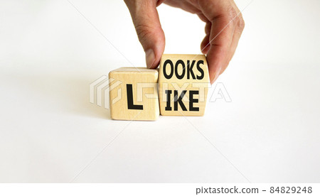 Looks like symbol. Businessman turns a wooden cube with words 'Looks like'. Beautiful white background. Business, popular quotes and looks like concept. Copy space. Looks like symbol. Businessman turns a wooden cube with words 'Looks like'. Beautiful white background. Business, popular quotes and looks like concept. Copy space. 84829248