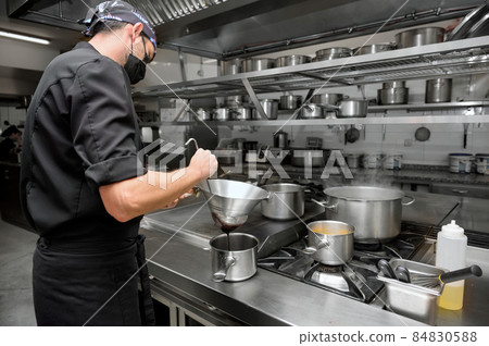 Chef cooking in modern industrial kitchen. Chef cooking in modern industrial kitchen. 84830588