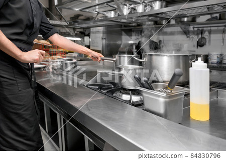 Unrecognizable Chef cooking in modern industrial kitchen. Unrecognizable Chef cooking in modern industrial kitchen. 84830796