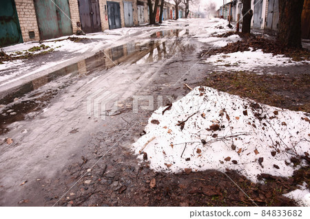 snow, water and ice are melting on the ground. spring is coming in the garage community. in Ukraine, Dnipropetrovsk region snow, water and ice are melting on the ground. spring is coming in the garage community. in Ukraine, Dnipropetrovsk region 84833682