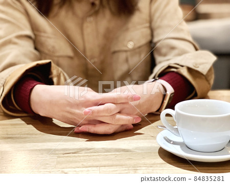 一位女士在咖啡館的咖啡杯旁交叉手指 一位女士在咖啡館的咖啡杯旁交叉手指 84835281