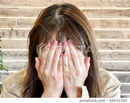 The front of a woman who covers her face with both hands The front of a woman who covers her face with both hands 84835384