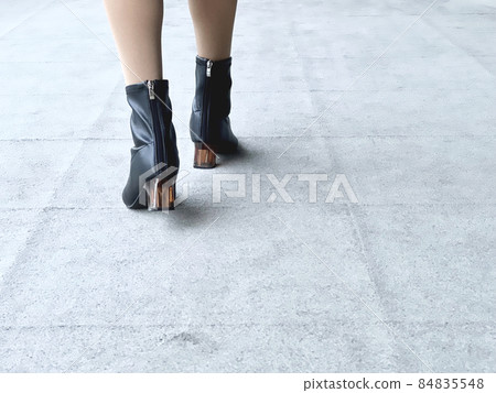 Women's feet in boots walking on the carpet floor 84835548