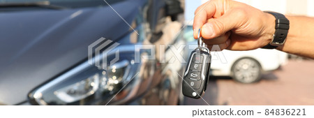 Male hand holding keys near new car closeup 84836221