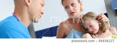 Doctor examining sick little girl in hotel room. Child sitting on lap of mother 84836227