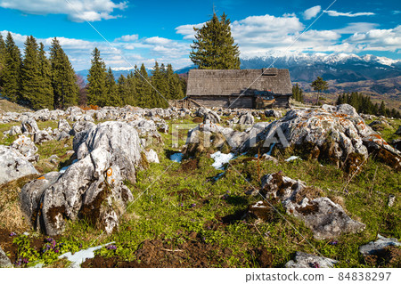 Wooden hut on the field and snowy mountains in background 84838297