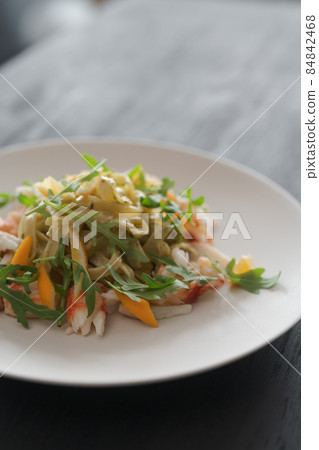 Fettuccine pasta with crab and arugula on black wood table Fettuccine pasta with crab and arugula on black wood table 84842468