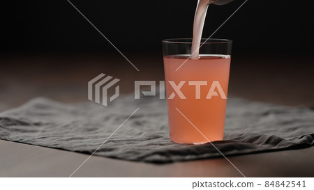 pour guava drink from can into tumbler glass on table 84842541