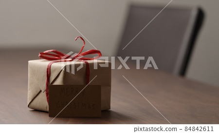 brown paper gift box with red bow on wood table with paper card 84842611