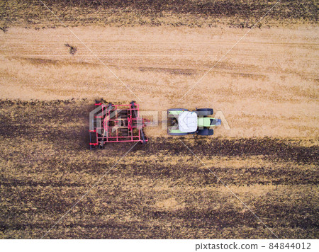 Harvesting in the field. Aerial view. Land cultivation with a tractor 84844012