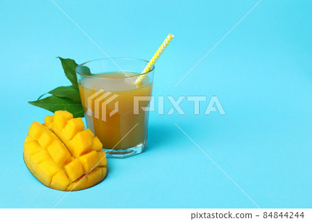 Ripe mango fruit and juice on blue background Ripe mango fruit and juice on blue background 84844244